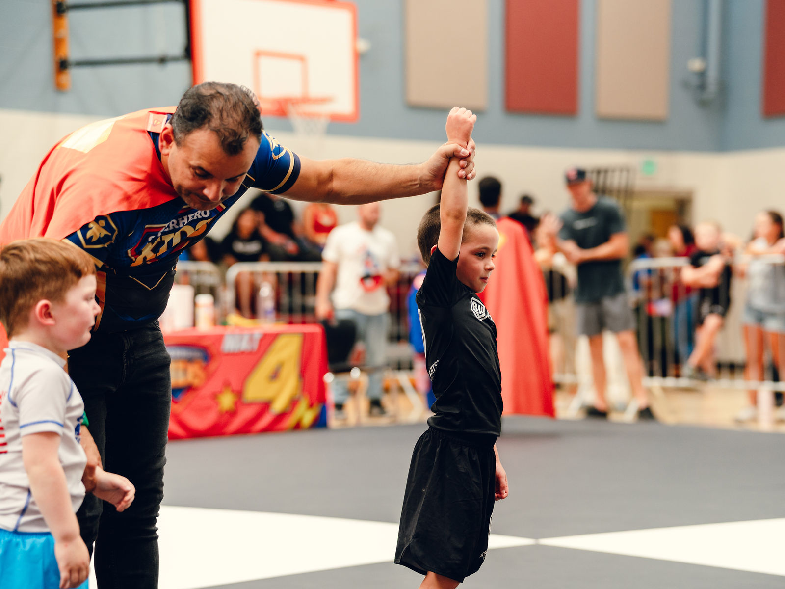 A referee raises the hand of a young Jiu-Jitsu athlete after his match